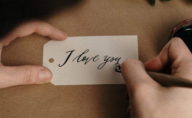 Person writing I love you on a label card
