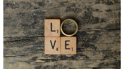 Block letters that spell out love on a table with a wedding ring to represent the 'O'