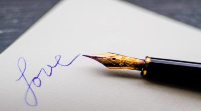 a black and gold pen that wrote "love" in blue on a piece of paper